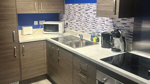 A modern kitchen with wooden cabinets, a stainless steel sink, a microwave, and a built-in oven.