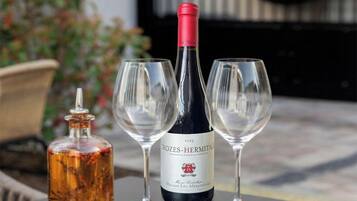 Een pizza op een houten plank, een fles Crozes-Hermitage wijn, en twee lege wijnglazen op een tafel.