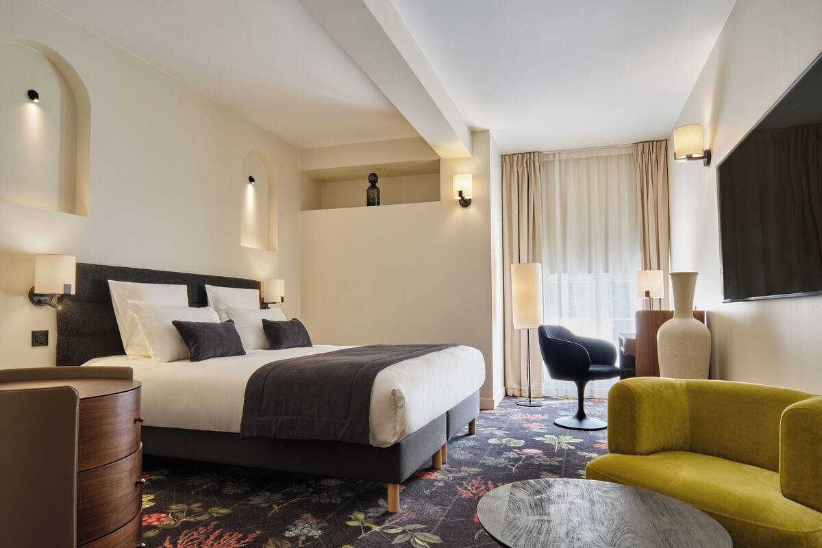 Une chambre d’hôtel avec un grand lit, un bureau, une chaise et un canapé.