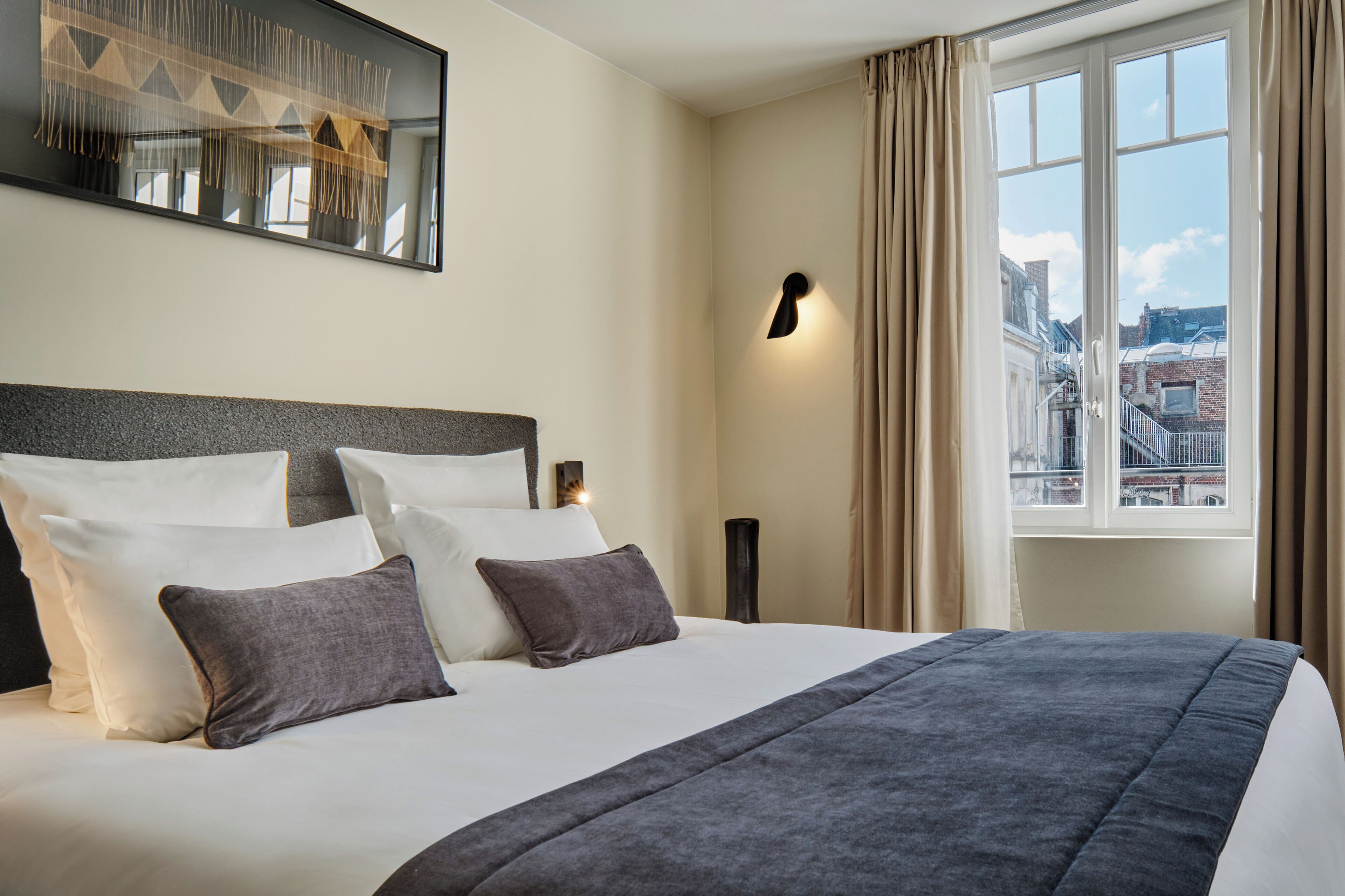 Ein Hotelzimmer mit einem großen Bett, Blick auf die Stadt und modernem Design.