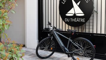Un vélo est garé devant un bâtiment sur lequel on peut lire l’inscription : « LES COULISSES DU THÉÂTRE ».