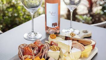 Une table avec une bouteille de vin, deux verres et une planche de charcuterie comprenant différents fromages et différentes sortes de viande.