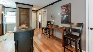 A kitchen with wooden cabinets, a dark island, and a dining area with a wooden table and chairs.