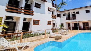 Un bâtiment moderne à deux étages doté d’une piscine, de mobilier d’extérieur et d’une terrasse clôturée.