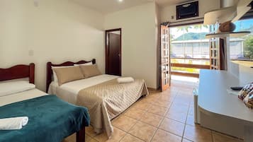 Habitación de hotel con dos camas, una mesita y vistas al exterior.
