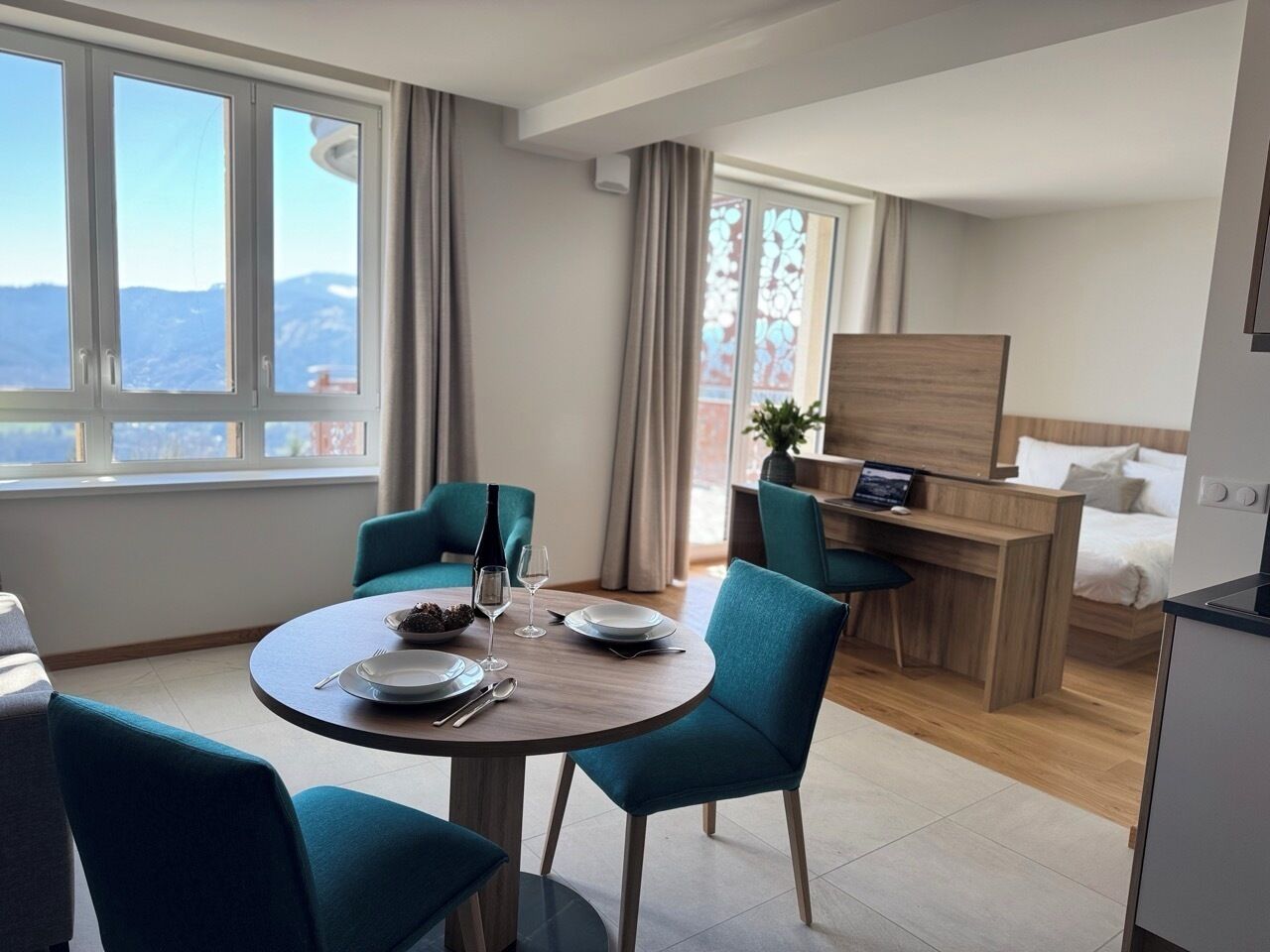 Una habitación de hotel moderna con zona de comedor, escritorio y cama.