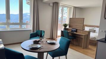 Una habitación de hotel moderna con zona de comedor, escritorio y cama.
