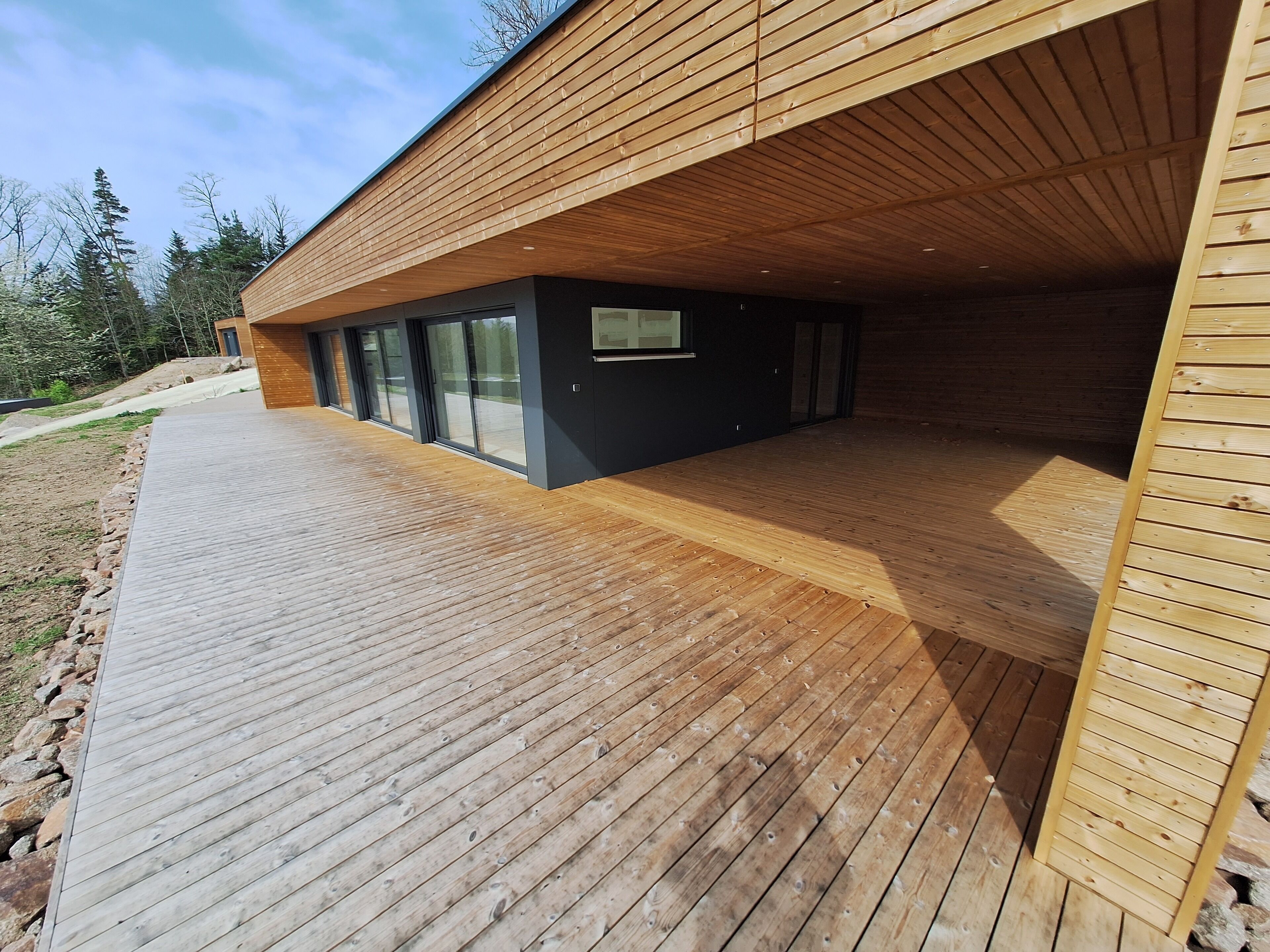 A modern building with a wooden deck and large glass windows.