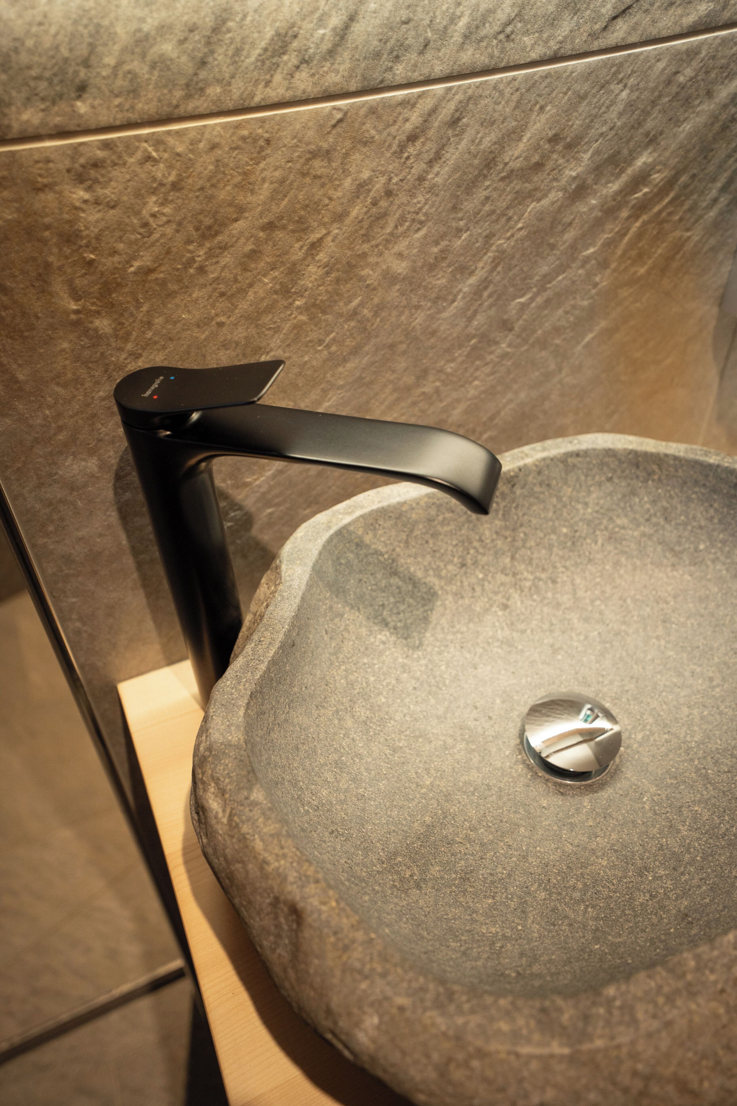 Un évier en pierre avec un robinet moderne dans une salle de bain.