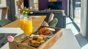 A modern dining area with a wooden table, a tray of food, and drinks.