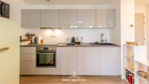 A modern kitchen with white cabinets, a built-in oven, and a sink.