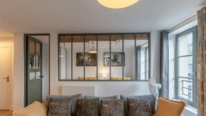 A living room with a sofa, cushions, a radiator, and artwork on the wall.
