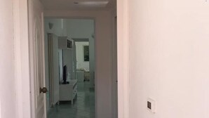 A narrow hallway with a patterned floor leading to a room with a bed and a dresser. - Olive Tree "Villa Nunzia" (Barano D'ischia)