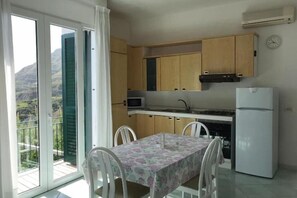 Una cucina con mobili in legno, un forno a microonde, un frigorifero e un tavolo da pranzo con sedie.