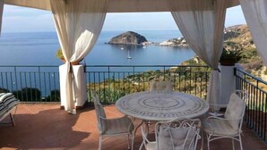 Un’area salotto all’aperto riparata, con vista sul mare e su una piccola isola.