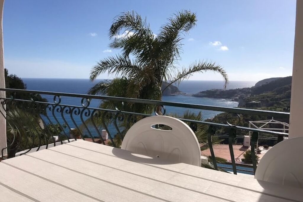 Un balcone con vista sull'oceano e palme.