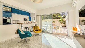 A modern living room with a kitchen, a dining area, and a balcony with outdoor furniture.