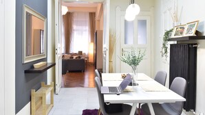 A modern living room with a sofa, a dining table with a laptop, and a fireplace. - Spacious 3-bedroom apartment in charming Budapest with AC, WiFi (Budapest)