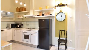A modern kitchen with white cabinets, a black refrigerator, and a dining area with a chair. - Spacious 3-bedroom apartment in charming Budapest with AC, WiFi (Budapest)