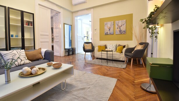 A living room with a sofa, coffee table, and a green side table. There is a fireplace and a painting on the wall. - Spacious 3-bedroom apartment in charming Budapest with AC, WiFi (Budapest)