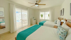 Une chambre d’hôtel avec deux lits, un ventilateur de plafond, une fenêtre avec des rideaux et une vue sur l’espace extérieur.