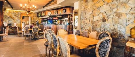 Un restaurante con pared de piedra, techo de madera y una zona de bar.