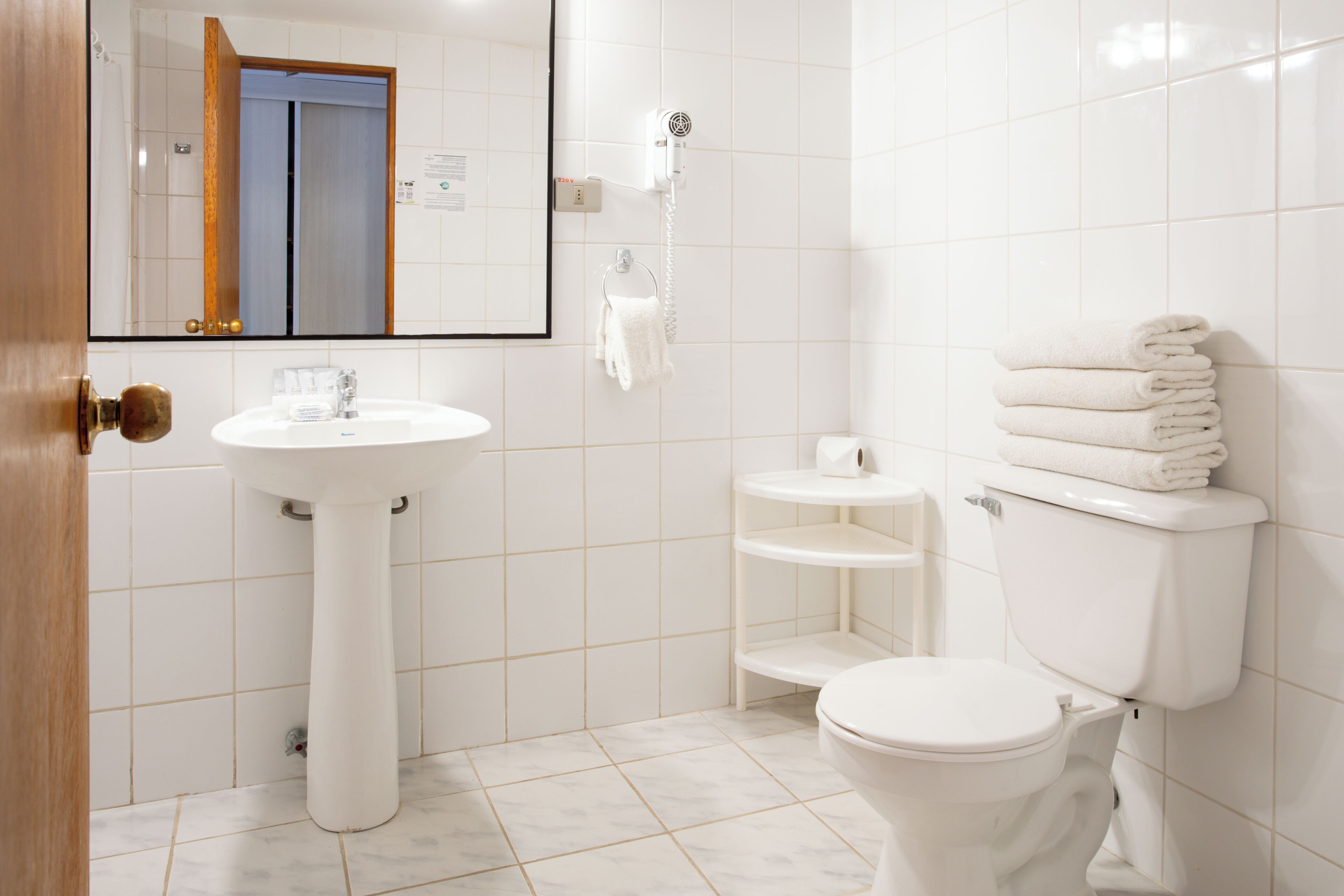 A modern bathroom with a pedestal sink, toilet, and a towel rack.