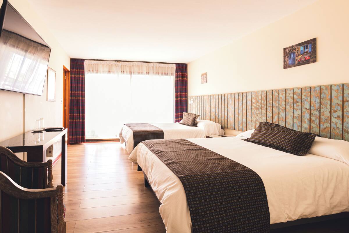 Ein Hotelzimmer mit zwei Betten, einem Schreibtisch und einem Fernseher.