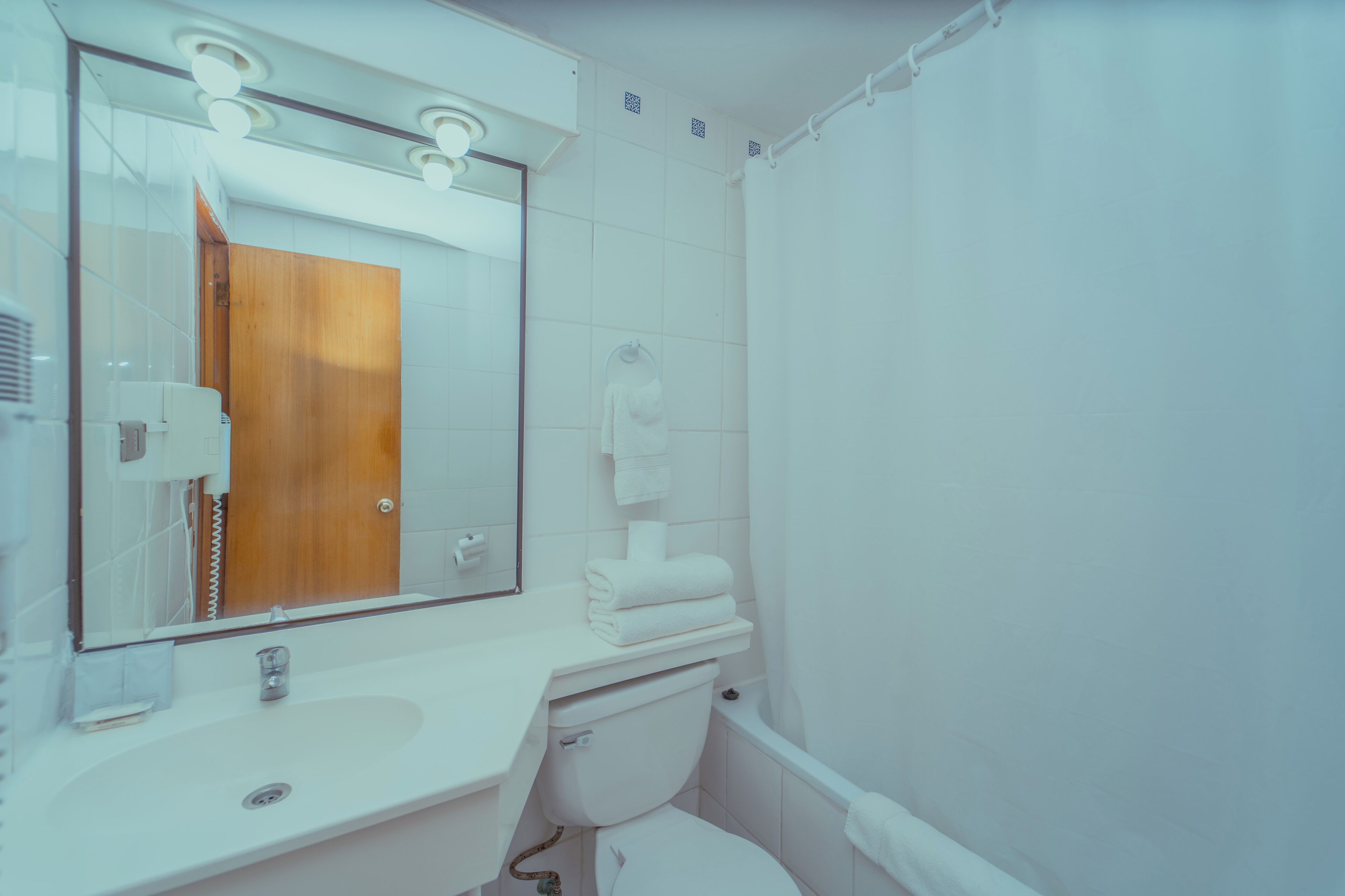 Un baño con lavamanos, espejo e inodoro blancos.