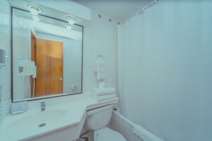 Un baño con lavamanos, espejo e inodoro blancos.