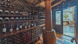A wine cellar with wooden shelves and barrels, a large wooden column, and a view of the outside. - Hotel Canto del Mar (La Serena)