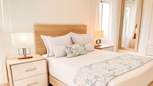 A neatly arranged bedroom with a wooden headboard, a bed with a star-patterned bedspread, a bedside table with a lamp, and a nightstand with a drawer. - Harmonious 2-bedroom Apartment with AC, WiFi & Balcony in marvelous Puerto Plata (Puerto Plata)