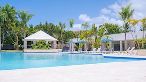 A swimming pool with lounge chairs and umbrellas, surrounded by palm trees and a gazebo. - Harmonious 2-bedroom Apartment with AC, WiFi & Balcony in marvelous Puerto Plata (Puerto Plata)