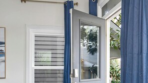 Een kamer met een blauwe deur, een raam met blauwe lijst, een blauwe bank en een bijzettafeltje van gestructureerd metaal.