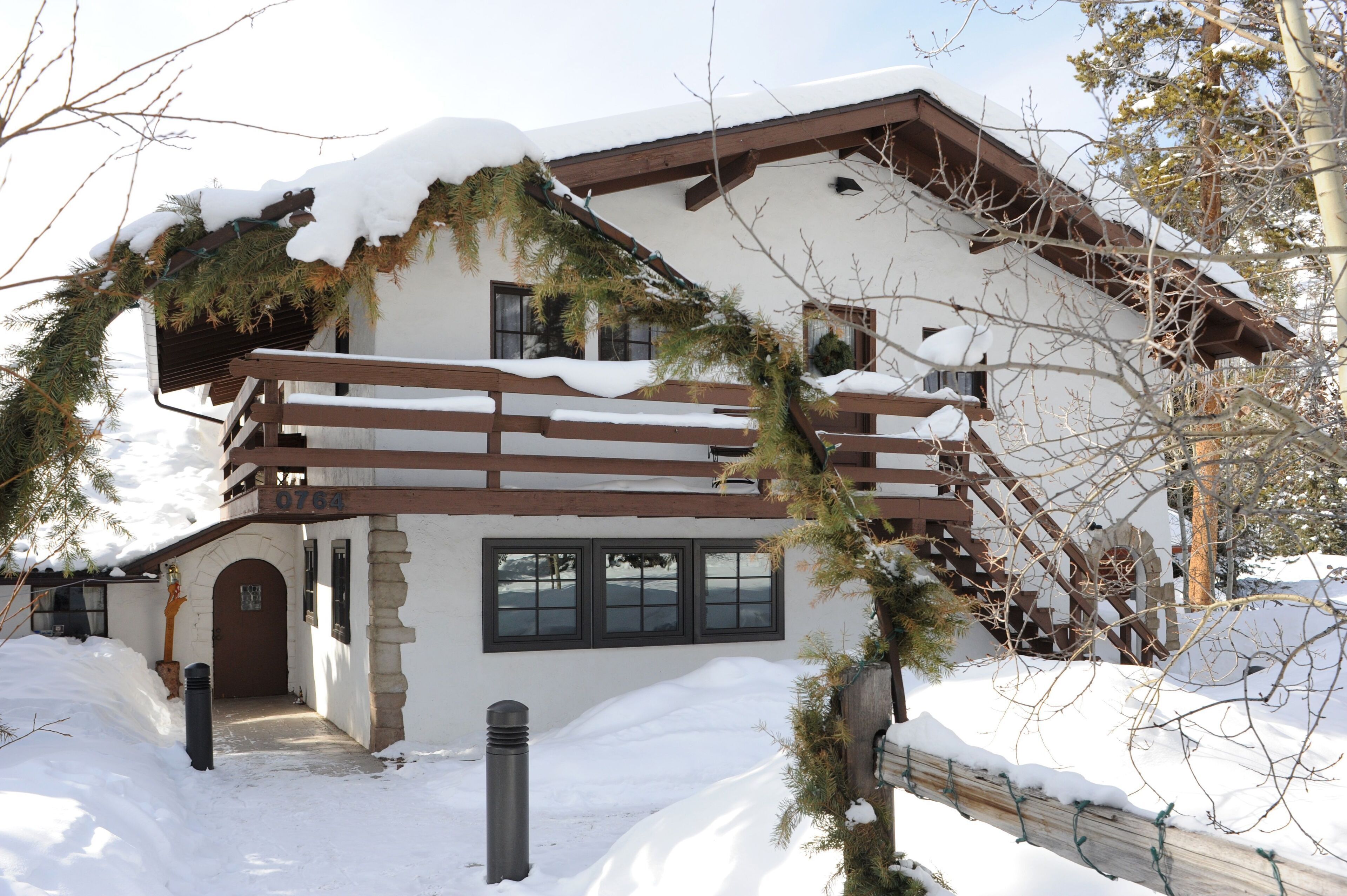 Un chalet à deux étages, doté d’un balcon en bois et d’un toit recouvert de neige.