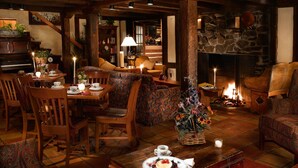 A cozy room with a fireplace, wooden furniture, and a dining area with a table set for tea. - Keystone Lodge Room | Historic Charm & Breakfast (Keystone)