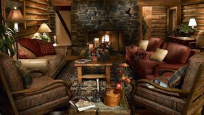 A cozy log cabin interior with a stone fireplace, wooden furniture, and a patterned rug. - Keystone Lodge Room | Historic B&B & Breakfast (Keystone)