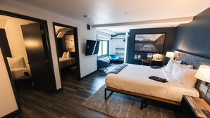 Una habitación de hotel moderna con una cama grande, un escritorio, una silla, un televisor y un cuadro en la pared.