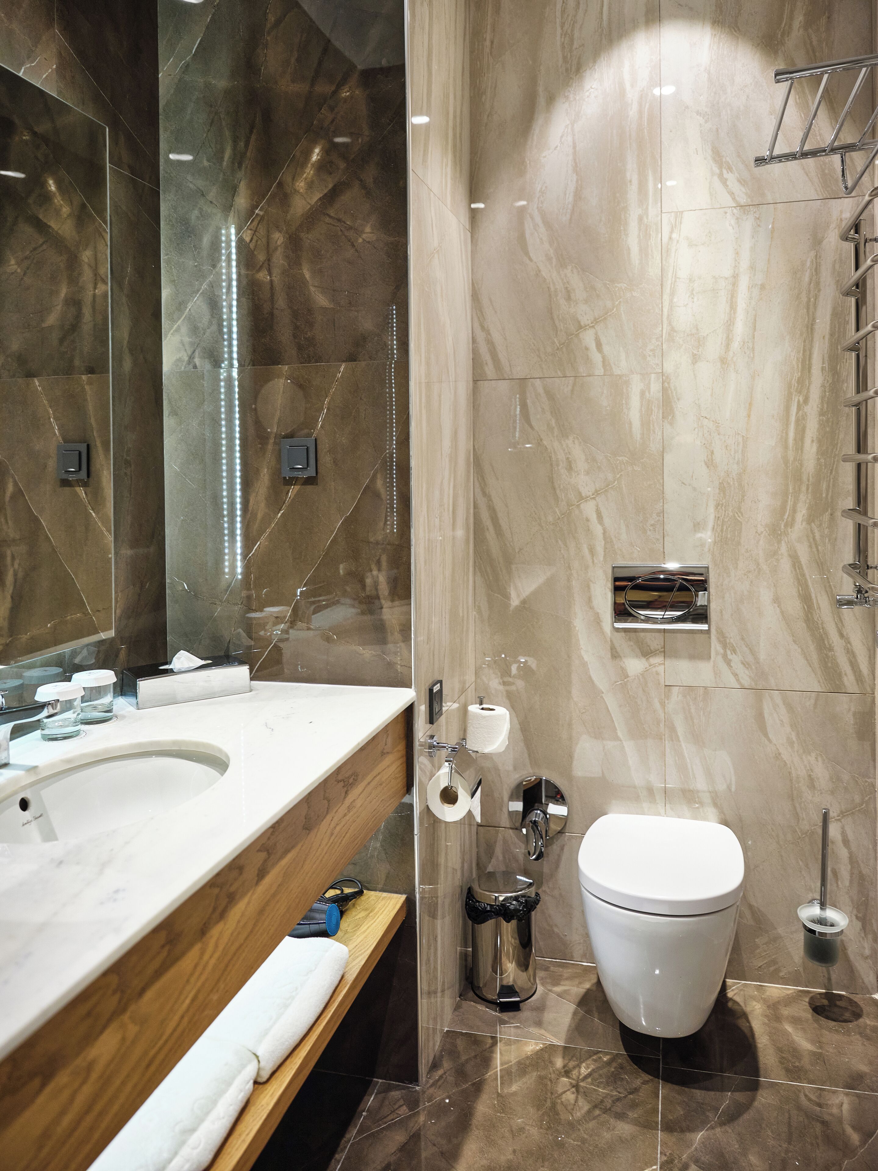A modern bathroom with a marble vanity, a toilet, and a glass shower enclosure.