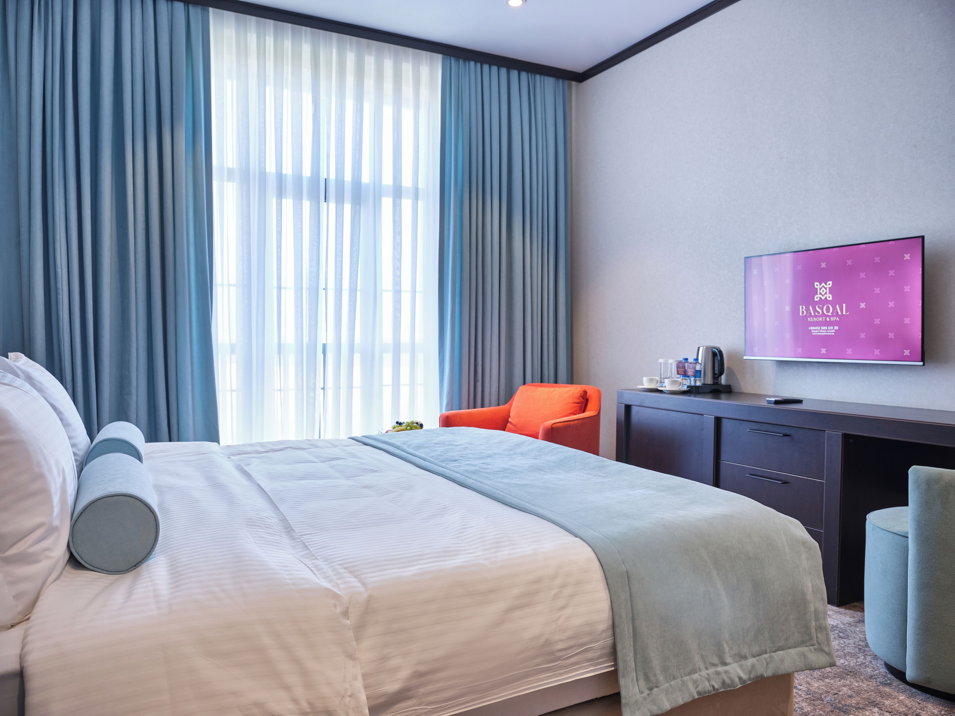 Een hotelkamer met een bed, een bureau, een stoel en een televisie aan de muur.
