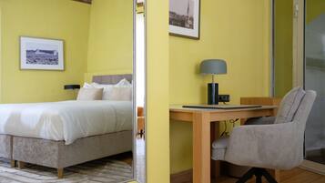 A hotel room with a bed, a desk, a chair, and a mirror.
