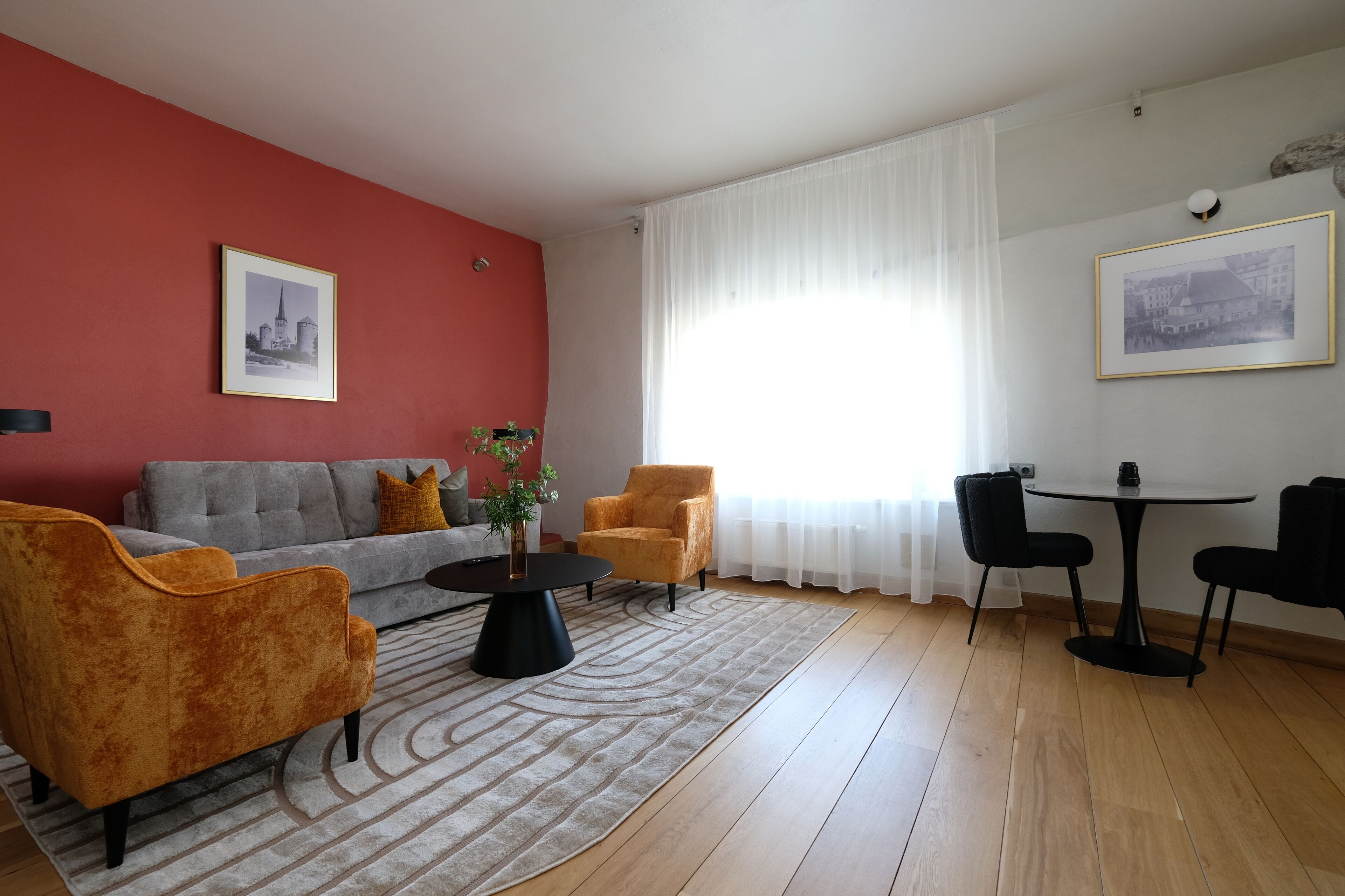 Una sala de estar con sofá, sillones, una mesa de centro y una mesa de comedor con sillas.