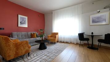 Una sala de estar con sofá, sillones, una mesa de centro y una mesa de comedor con sillas.