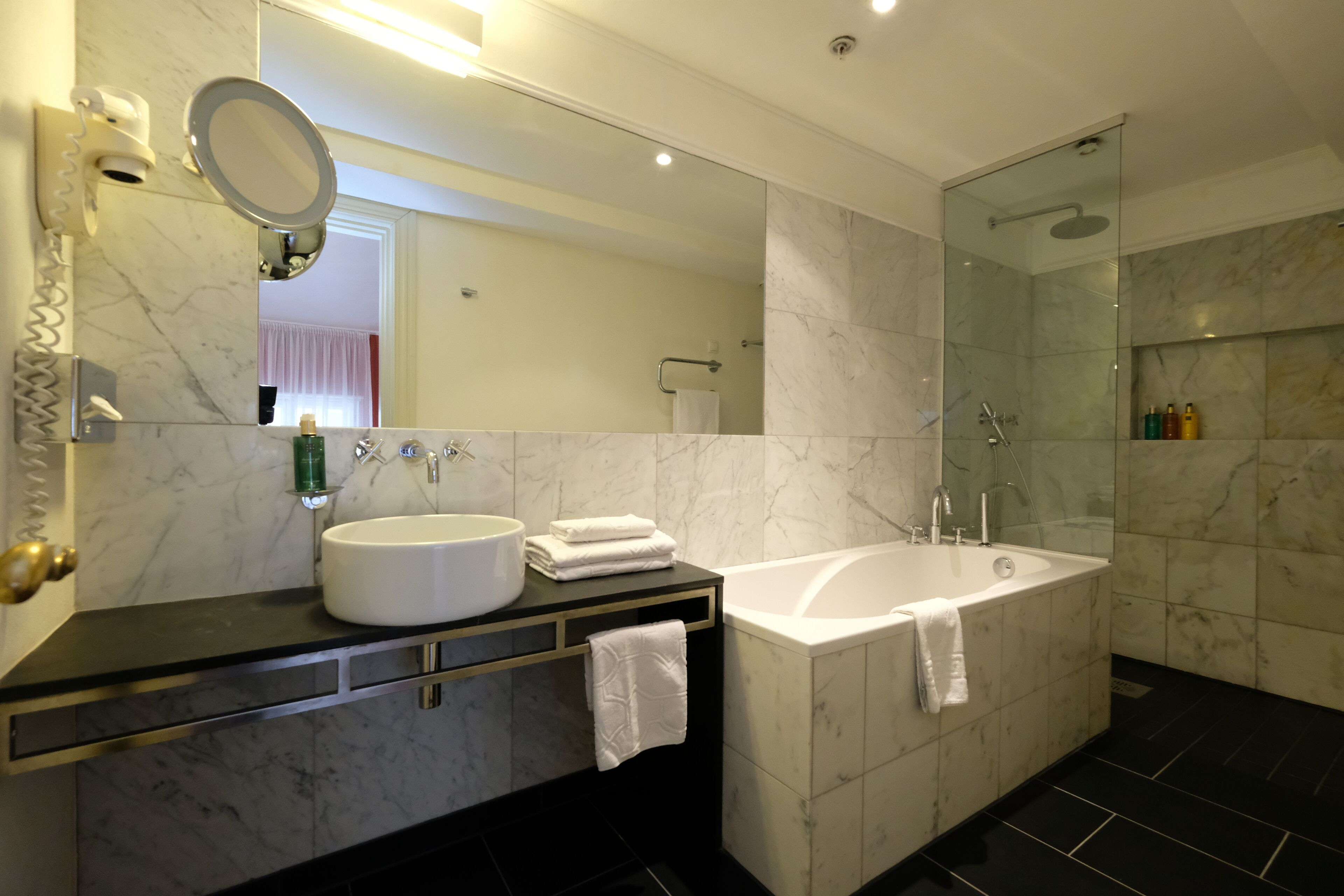 Un baño moderno con un espejo grande, un lavabo, una bañera y una ducha.