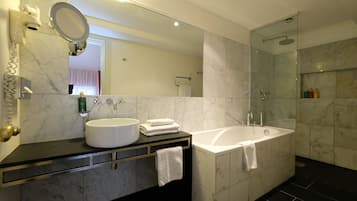 A modern bathroom with a large mirror, a sink, a bathtub, and a shower.