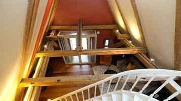 Un escalier en bois avec une rampe blanche menant à une mezzanine dont le plafond est rouge.