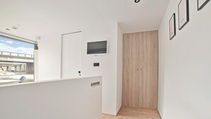 A modern interior with a wooden panel wall, a mounted TV, and a view of a bridge through a window. - HouseBoat the NEW LAKE (Amsterdam)