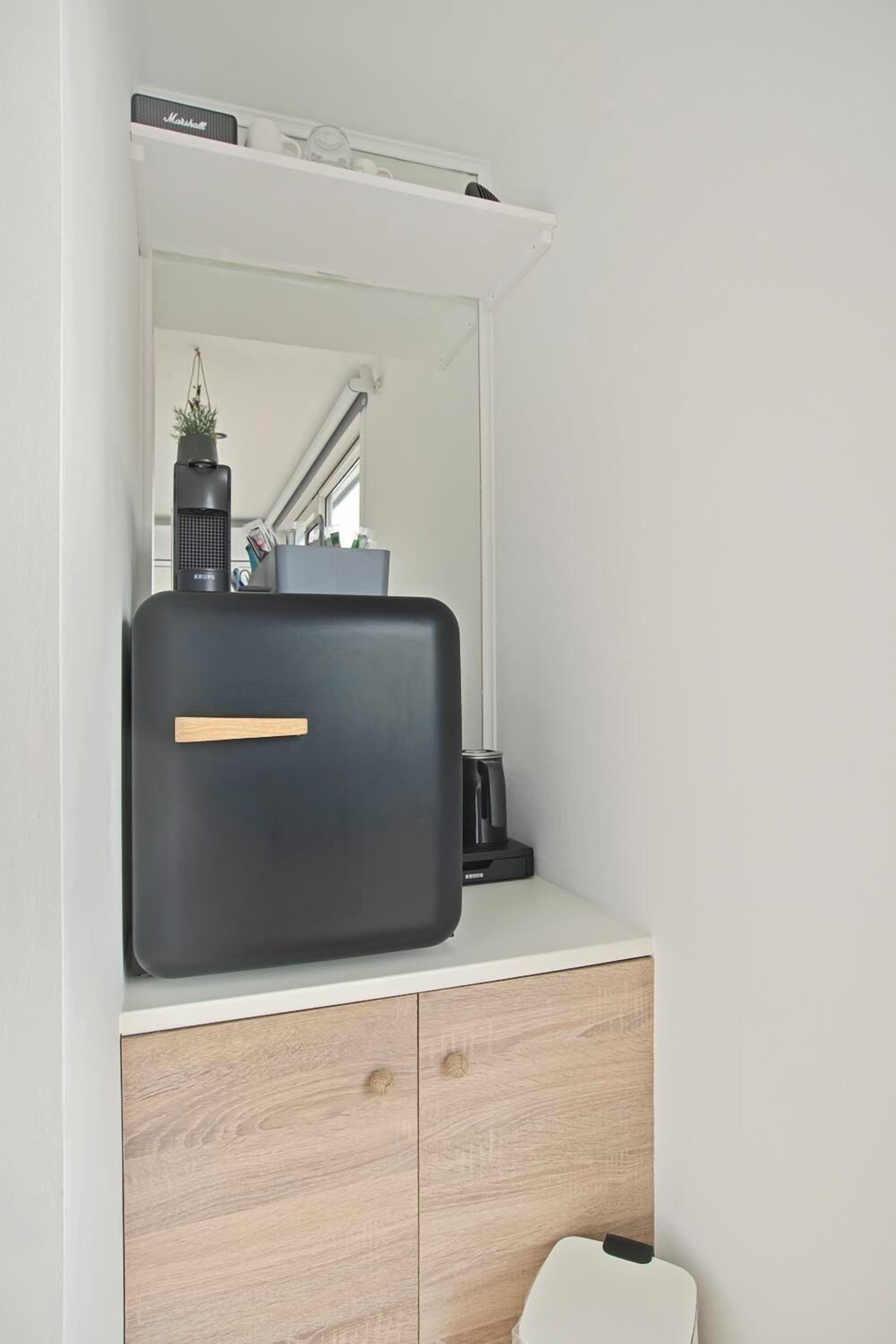 A bathroom with a white vanity, a black suitcase on top, and a mirror above.