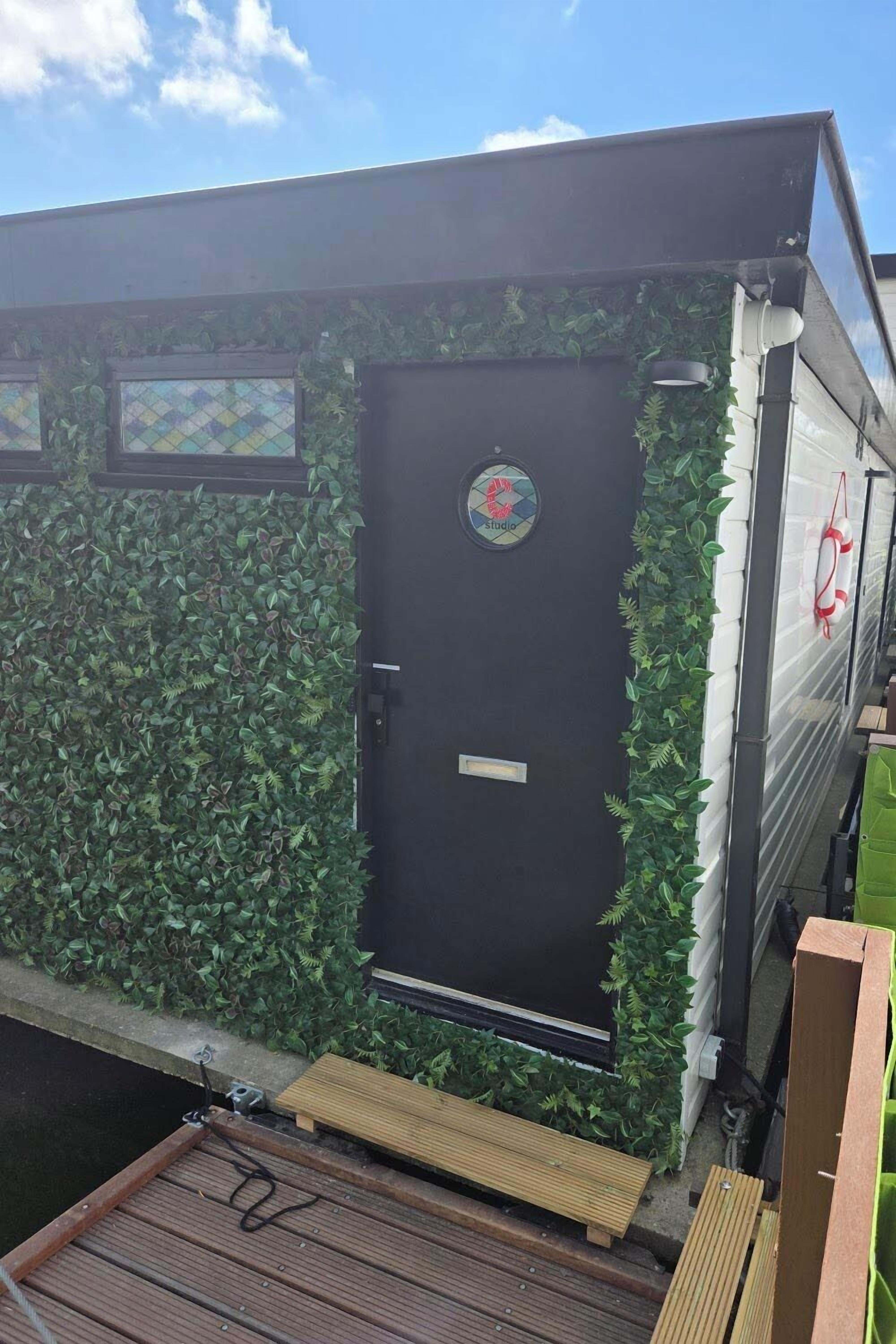 A small, enclosed structure with a black door, a logo on the door, and a small window above the door.