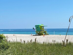 Une tour de surveillance sur une plage, avec une eau d’un bleu limpide et un ciel dégagé.